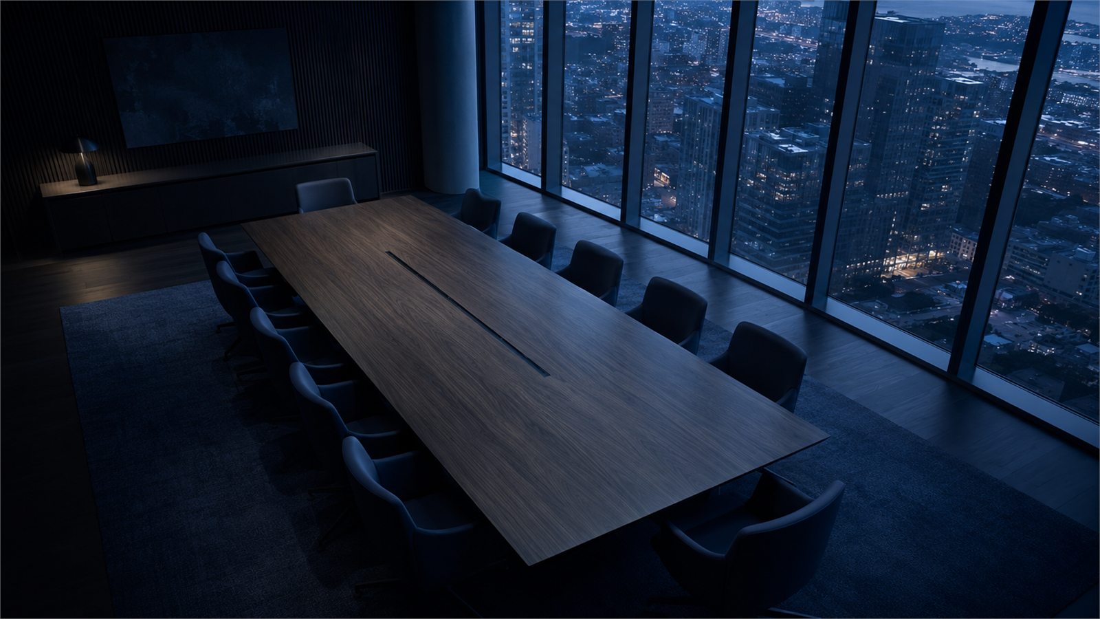 A boardroom table beside a window overlooking city lights at night.