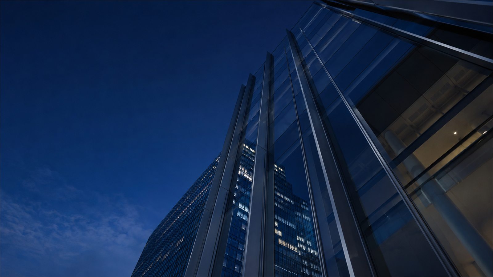 A glass tower photographed looking upward at blue hour.