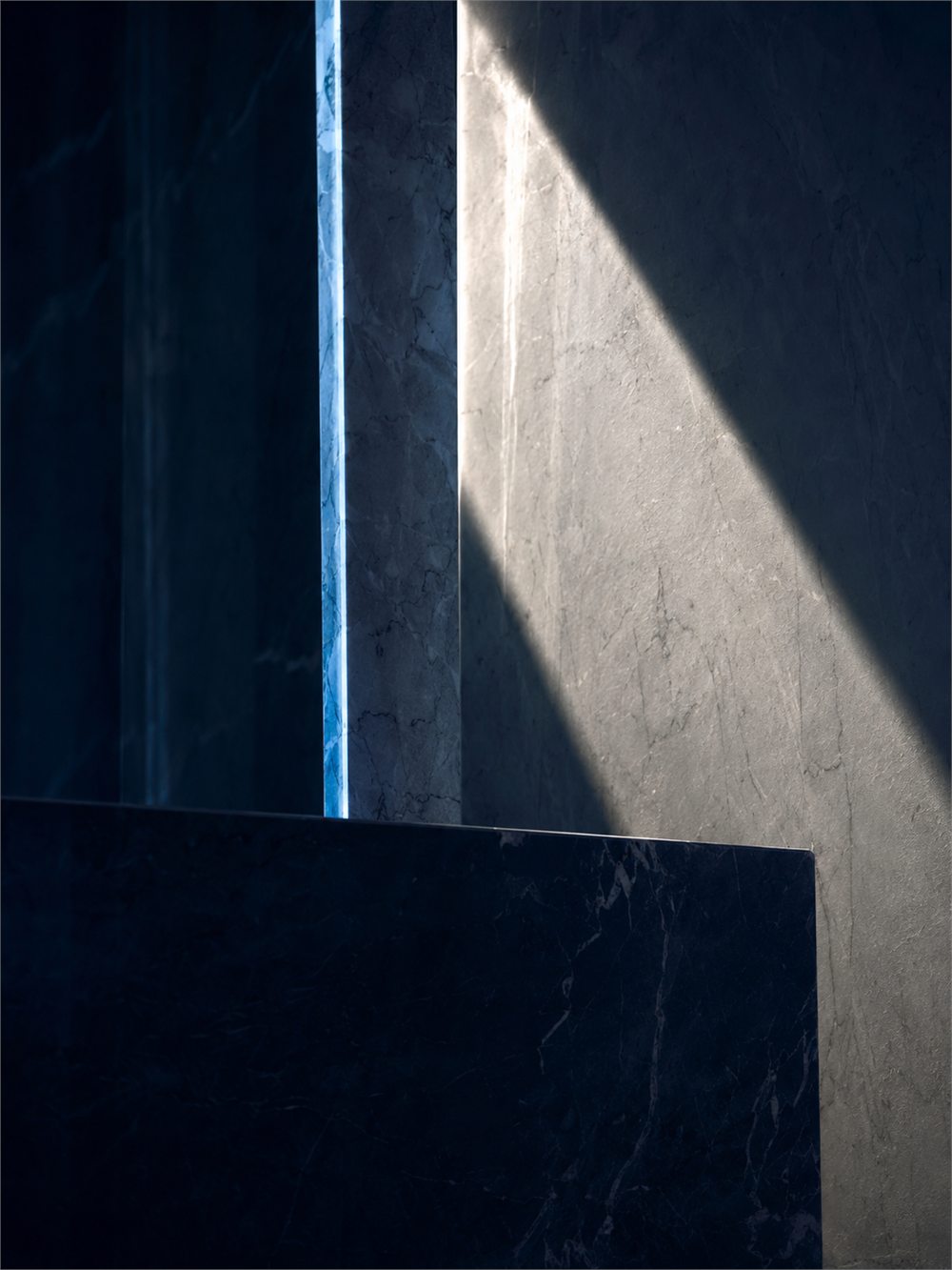 A shaft of daylight falling across dark marble architecture.