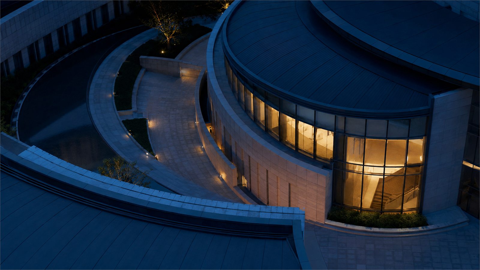 Montlior House, a curved stone building lit from within at night.