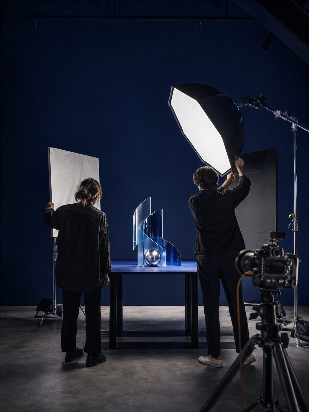 A photographer positioning a softbox light over a product set in the Montlior Media studio.