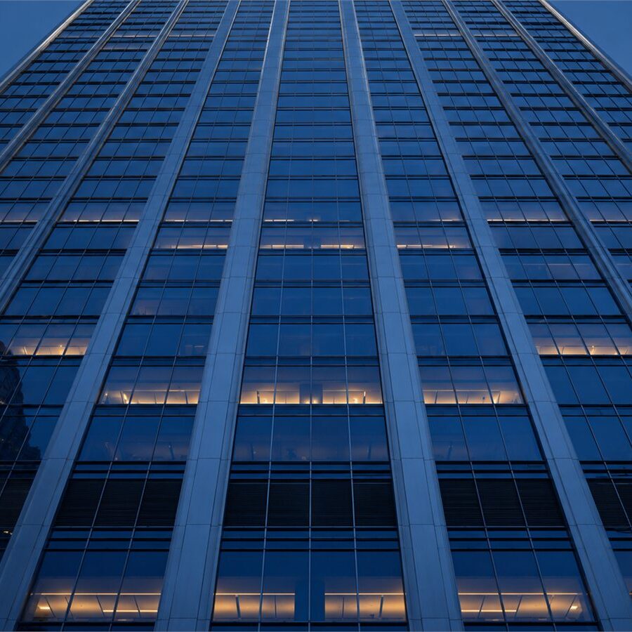 A symmetrical skyscraper facade photographed from below at dusk.